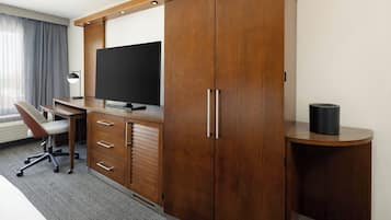 Habitación de hotel con escritorio de madera, televisión de pantalla plana, una silla y armario.