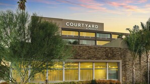 Un hotel Courtyard by Marriott con fachada de piedra, ventanas grandes y un estacionamiento.