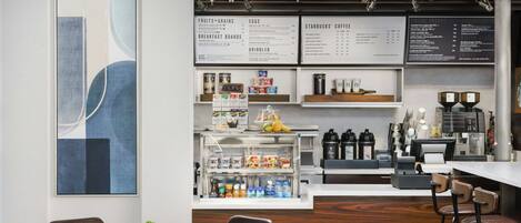 Ein modernes Café-Interieur mit einer zentralen Theke, einer Sitzgegend und Speisekarten.
