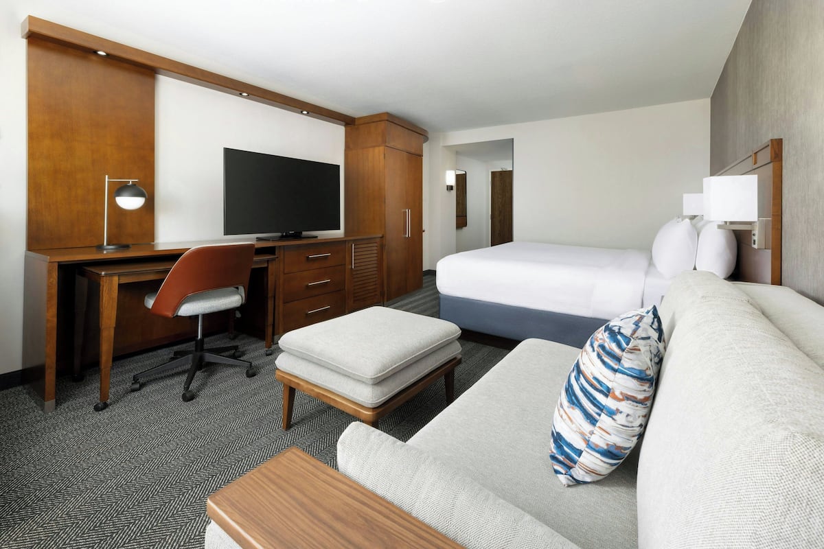Ein Hotelzimmer mit einem Bett, einem Schreibtisch mit Stuhl, einem Fernseher und einem kleinen Tisch.