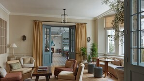 A spacious living room with a large window, a dining area, and a kitchen visible through an open door.