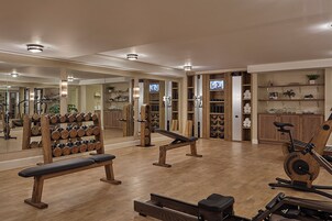 Ein Fitnessraum mit Holzboden, Trainingsgeräten und einer Spiegelwand.