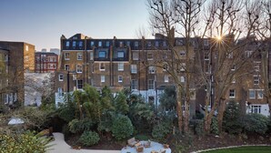 Un immeuble résidentiel à plusieurs étages doté d’une cour intérieure aménagée avec des espaces de détente en plein air et de la verdure.