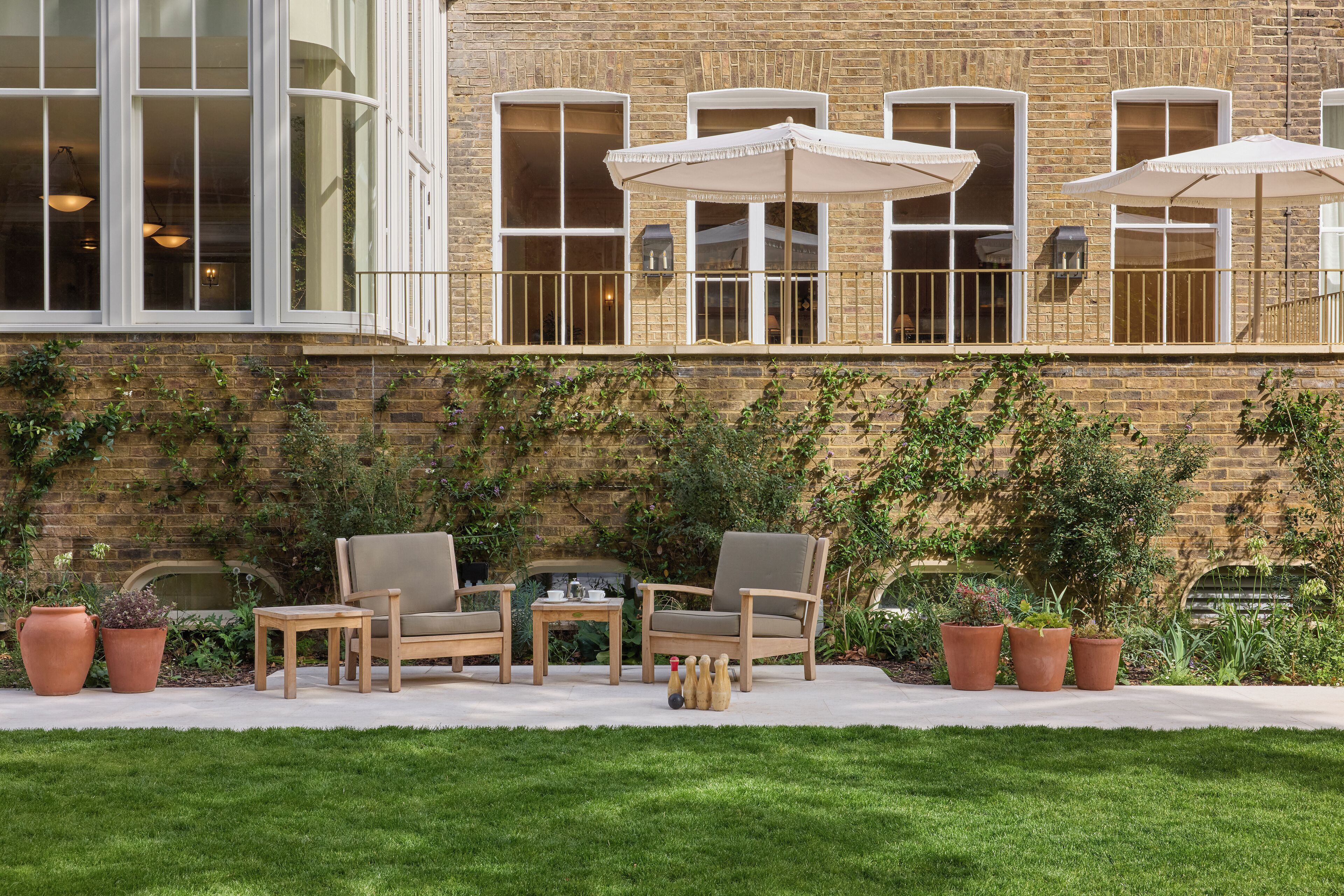 A brick building with large windows and a balcony with outdoor furniture and umbrellas.