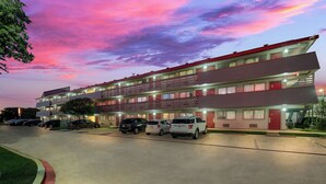 A multi-story motel with a parking lot, featuring a flat roof and a red and white facade. - Red Roof Inn Dallas - DFW Airport North (Irving)