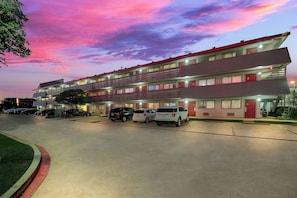 A multi-story motel with a parking lot, featuring a flat roof and a red and white facade. - Red Roof Inn Dallas - DFW Airport North (Irving)