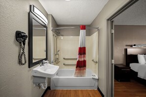 A bathroom with a bathtub, a sink, a mirror, a shower, and a telephone. - Red Roof Inn Dallas - DFW Airport North (Irving)