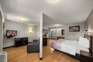 Una habitación de hotel con una cama, un escritorio, una silla, un televisor y un televisor de pared.