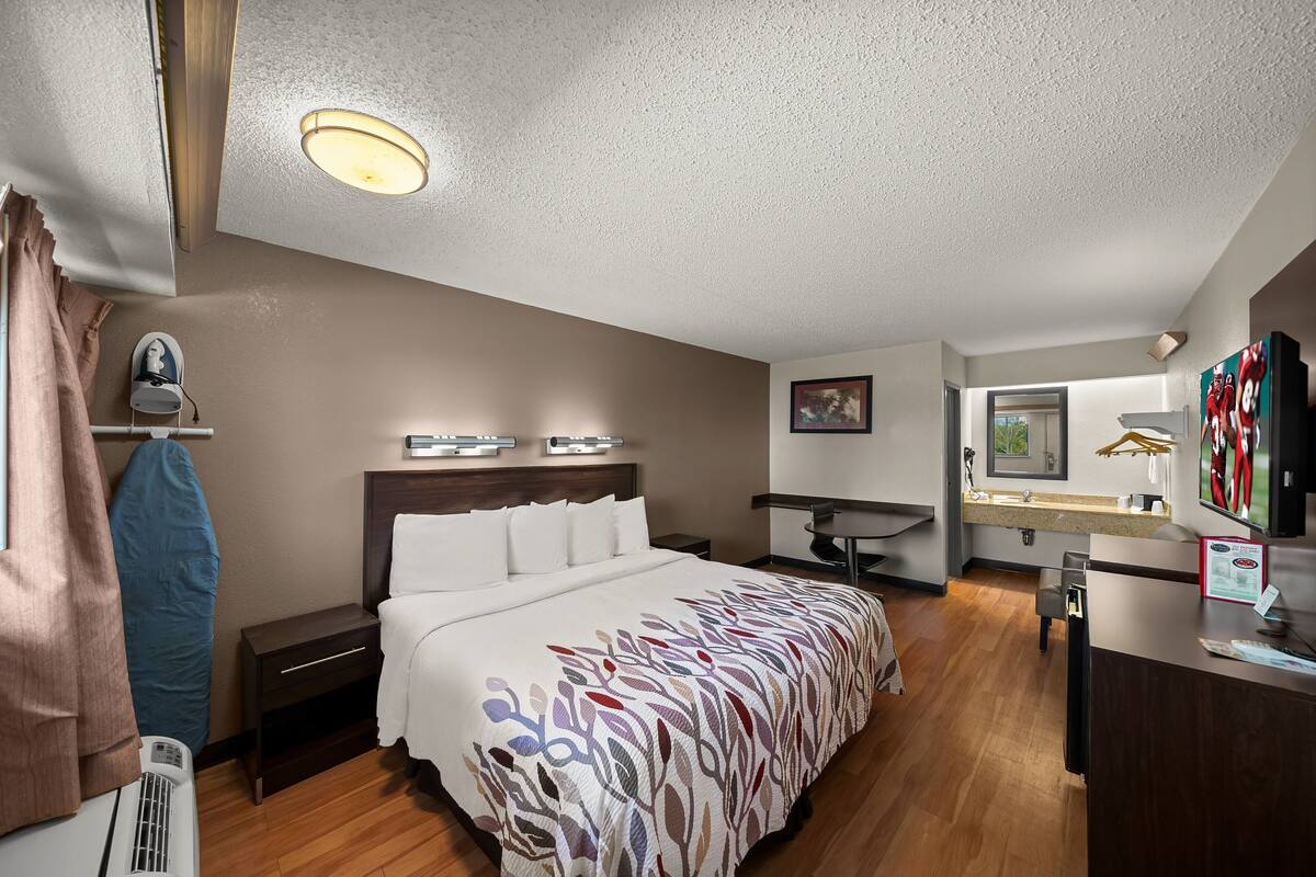 A hotel room with a bed, bedside table, desk, and a television.