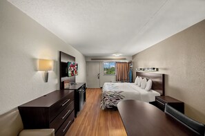 A hotel room with a bed, a desk, a chair, a TV, and a window with curtains. - Red Roof Inn Dallas - DFW Airport North (Irving)