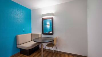 A corner room with a blue wall, a small table, a chair, and a mirror.