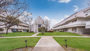 A modern apartment building with a central courtyard, multiple balconies, and a clear sky. - Motel 6 Irving, TX - Irving DFW Airport East (Irving)