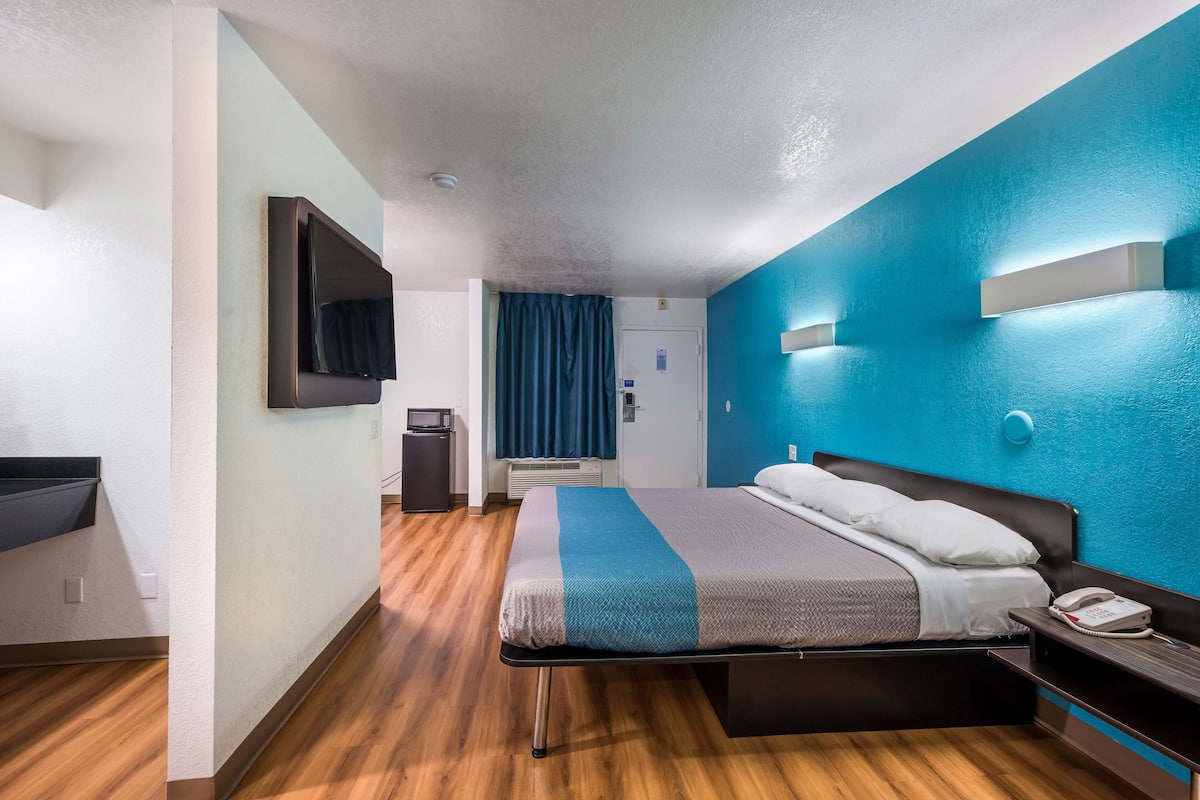 Habitación de hotel con cama, escritorio, televisor de pantalla plana, teléfono y baño.