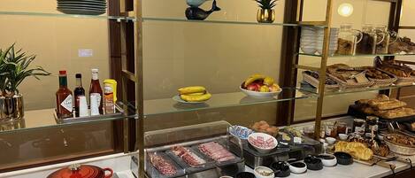 A buffet area with various food items, condiments, and a meat carving station.
