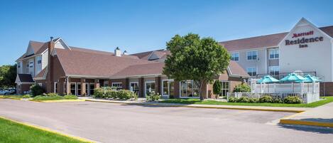 A Marriott Residence Inn with a brick facade, large windows, and a covered outdoor seating area.