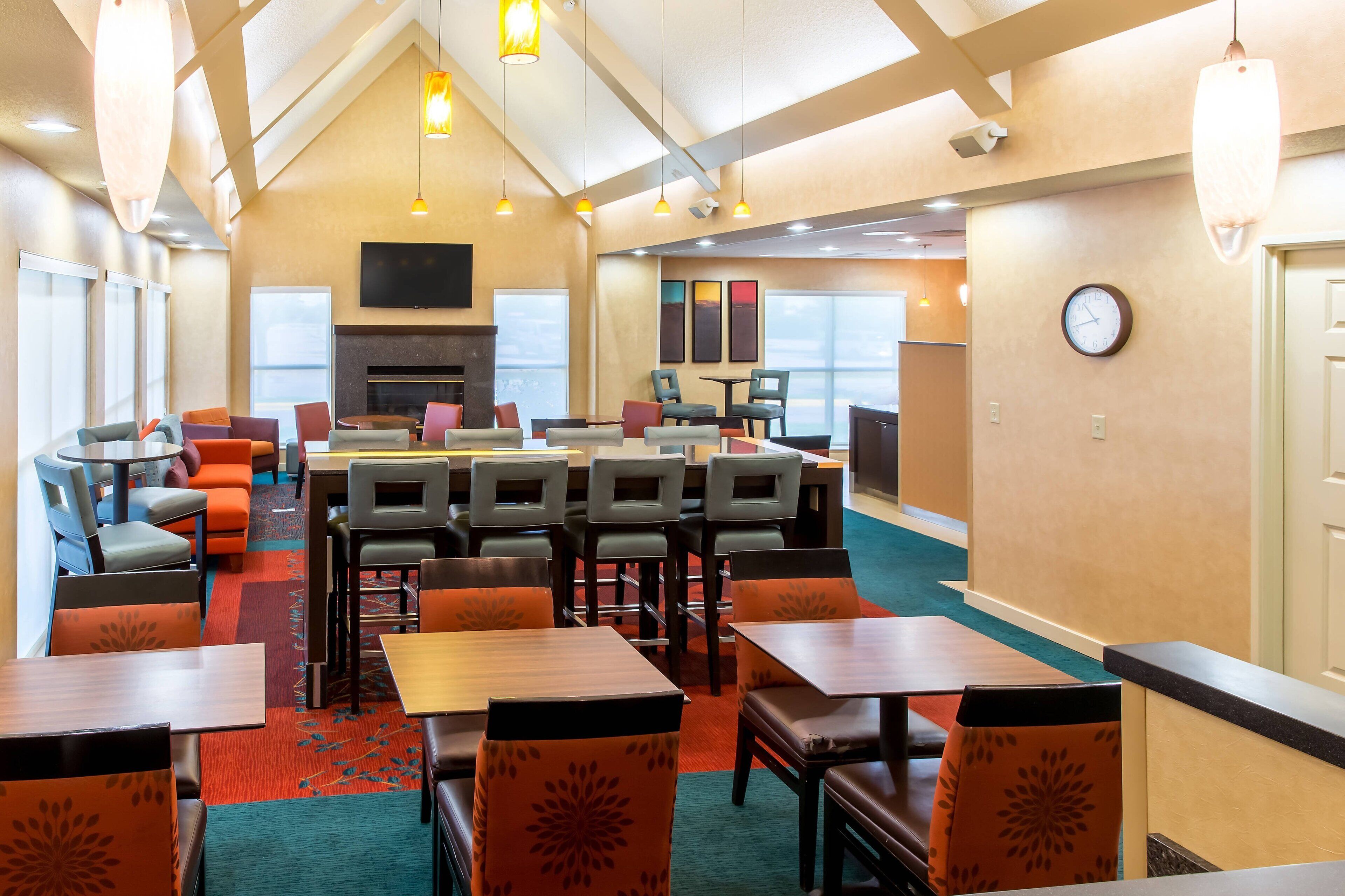 A hotel lobby with a fireplace, multiple seating areas, and a large window providing natural light.