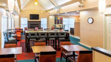A hotel lobby with a fireplace, multiple seating areas, and a large window providing natural light.