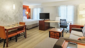A hotel room with a bed, a desk with a TV, a dining table, and a sofa. - Residence Inn Sioux Falls (Sioux Falls)