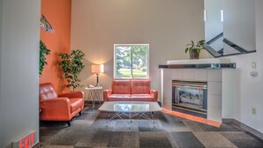 A modern living room with a fireplace, leather sofas, a coffee table, and a large window.