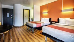 A hotel room with two beds, a desk, and a chair.