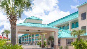 A hotel with a turquoise roof, multiple balconies, and a palm tree in the foreground. - Days Inn by Wyndham Gulfport (Gulfport)