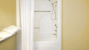 A bathroom with a bathtub, shower, and a towel rack. - Days Inn by Wyndham Gulfport (Gulfport)