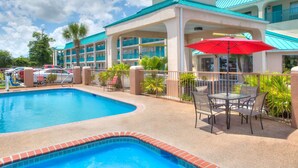 A hotel with a swimming pool, outdoor seating, and a covered patio area. - Days Inn by Wyndham Gulfport (Gulfport)