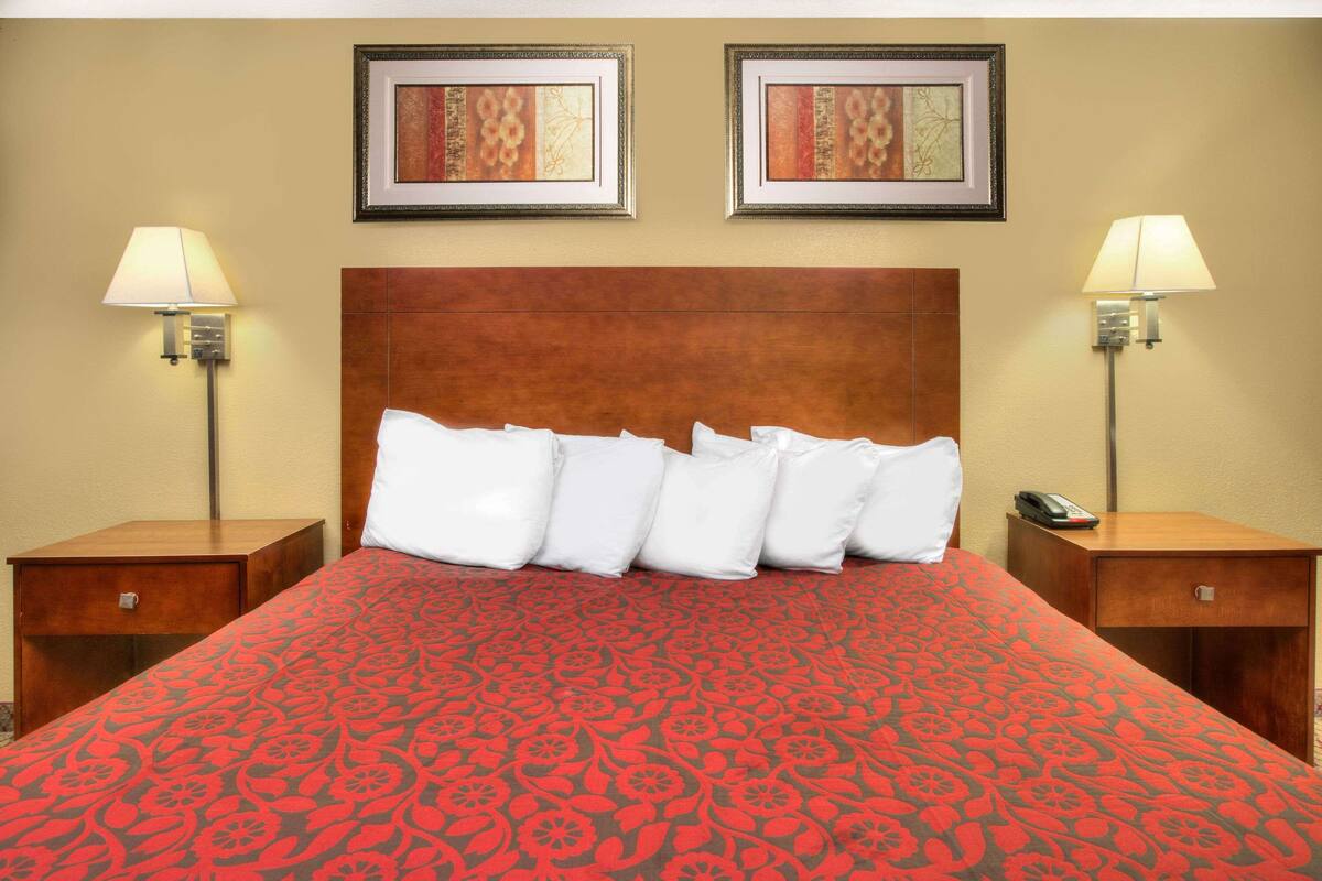 A hotel room with a large bed, two bedside tables, and two wall-mounted lamps.