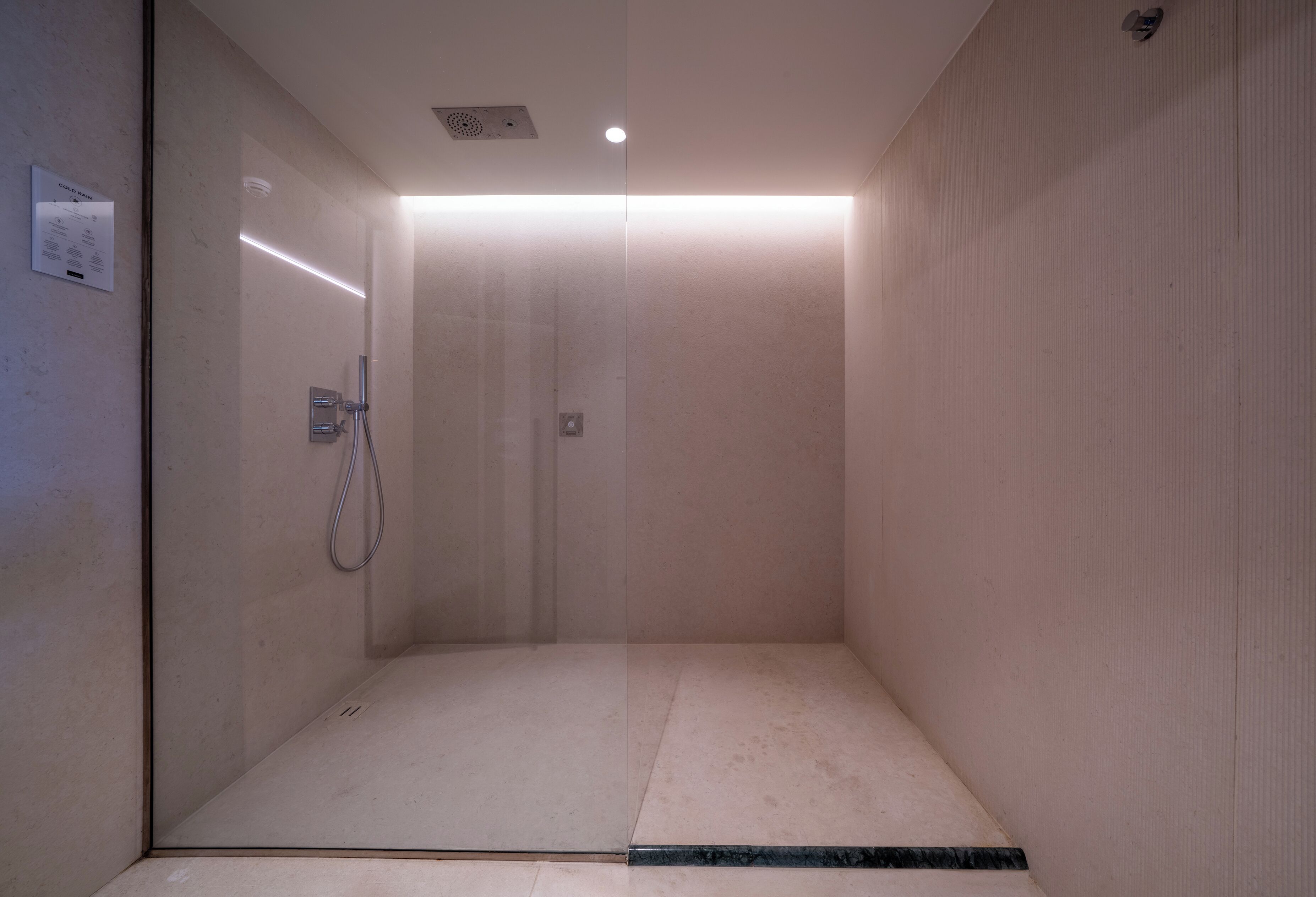 Ein modernes Duschbad mit Glastür, Handbrause und Bedienfeld.