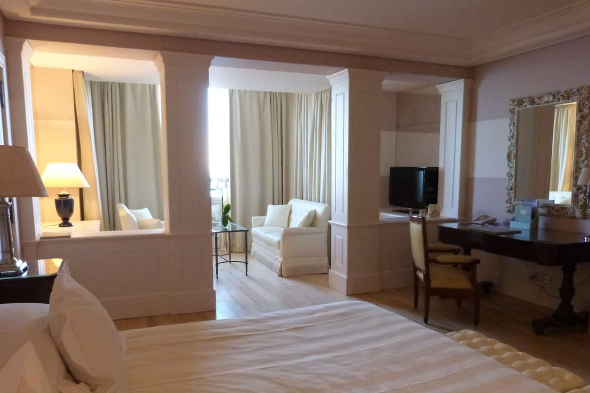 Hotellihuone, jossa on sänky, työpöytä, tuoli, televisio ja peili.