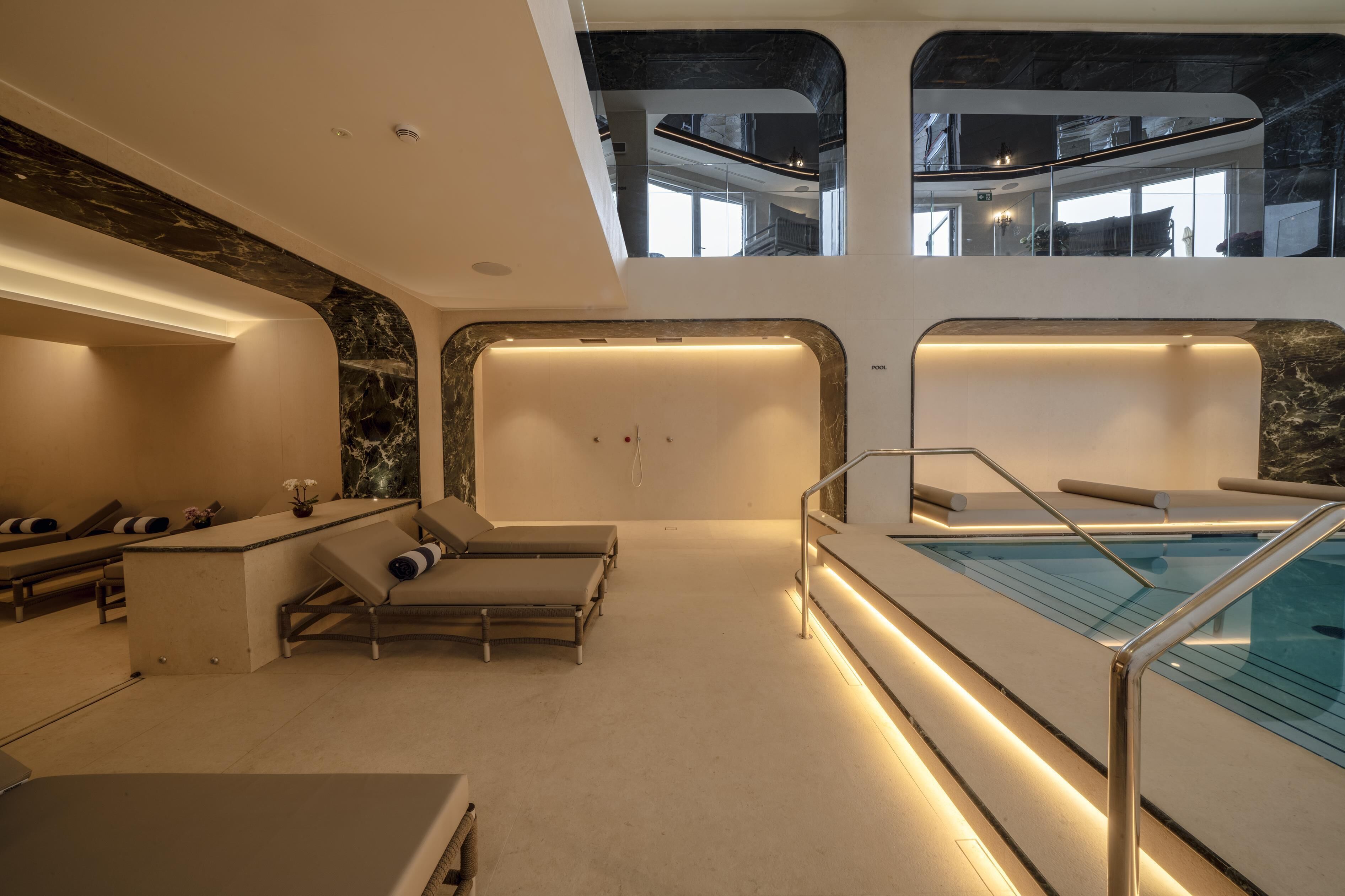 Un moderno espacio de spa con piscina, sillones de descanso y una recepción.