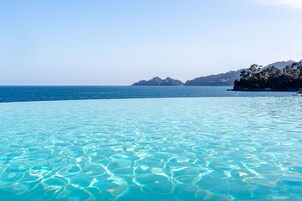 Una piscina al aire libre, sombrillas, sillones reclinables de piscina