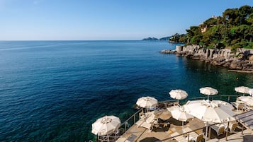 Privatstrand, schwarzer Sandstrand, Liegestühle, Sonnenschirme