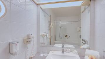 A modern bathroom with a glass-enclosed shower, a large mirror, and a sink with toiletries.