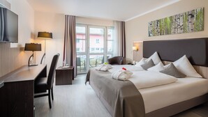 A hotel room with a bed, a desk, a chair, a TV, and a window with curtains. - Best Western Plus Parkhotel Erding (Erding)
