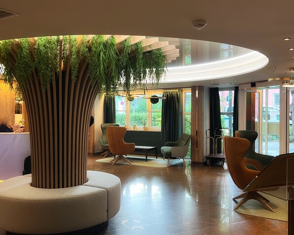 A modern lobby with a central tree, seating area, and large windows. - Best Western Plus Parkhotel Erding (Erding)