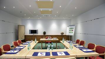 A conference room with a long table, red chairs, and a whiteboard.