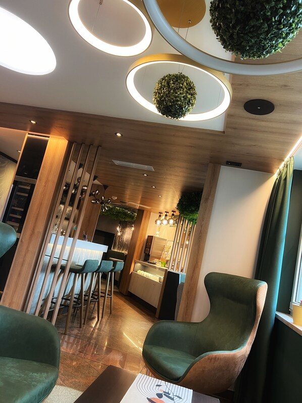 A modern interior with a wooden ceiling, circular lighting, a bar area, and green upholstered chairs. - Best Western Plus Parkhotel Erding (Erding)