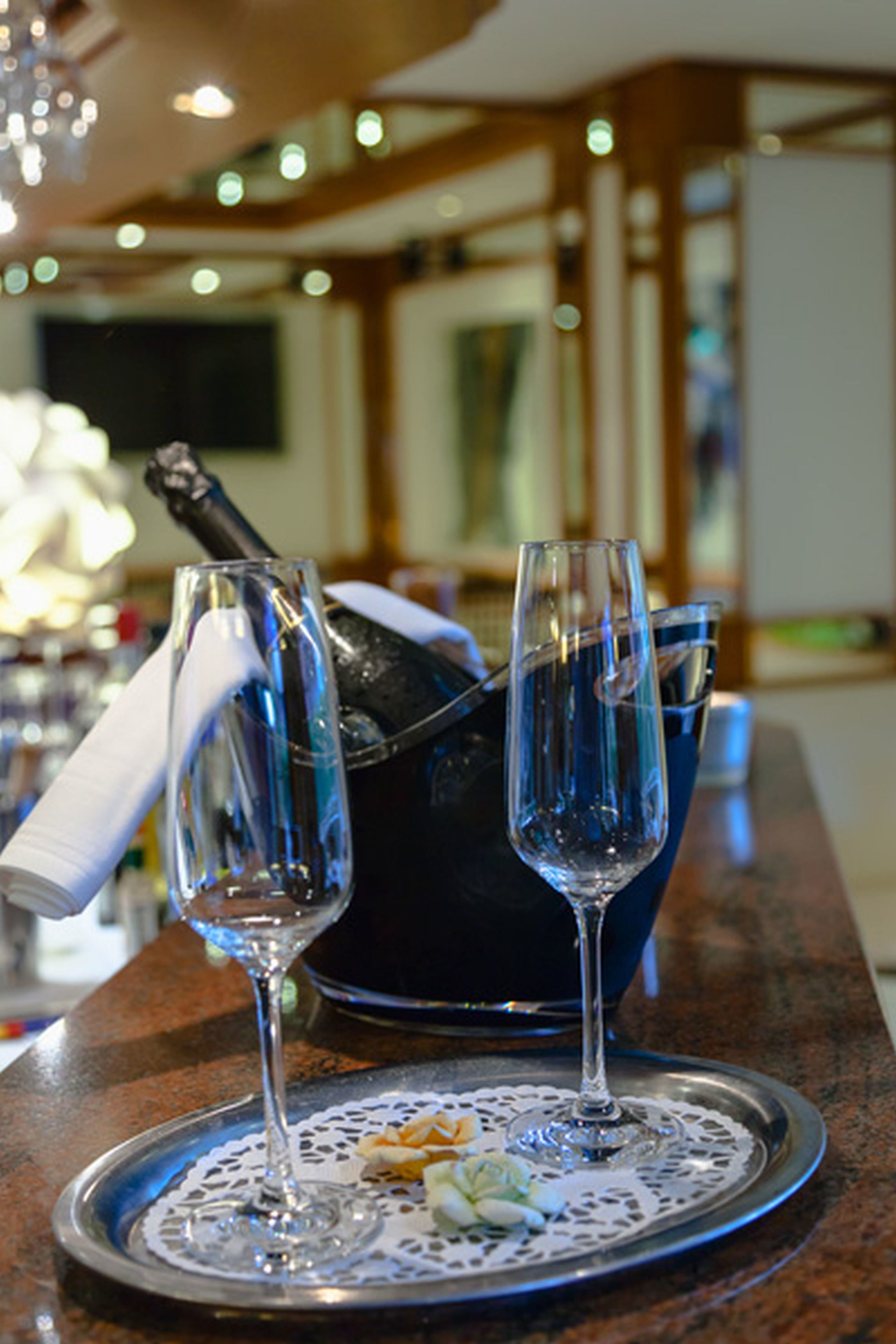 Una zona de bar con dos copas de champán sobre una bandeja, una botella de champán y un cubo azul.