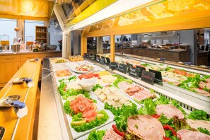 Un bufé con diversos tipos de carne y ensaladas.