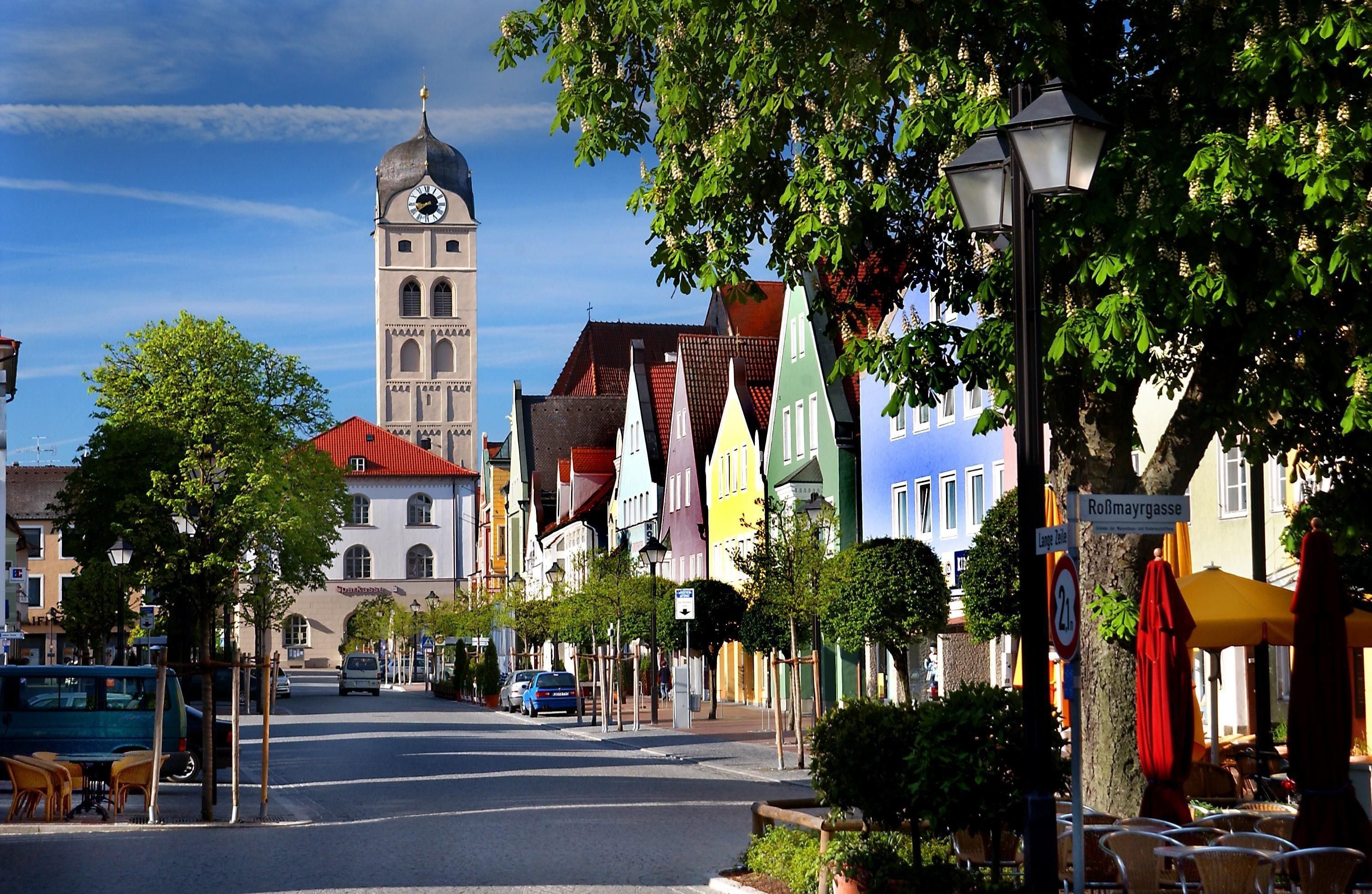 Eine Straße mit einem Glockenturm, bunten Gebäuden und blauem Himmel.