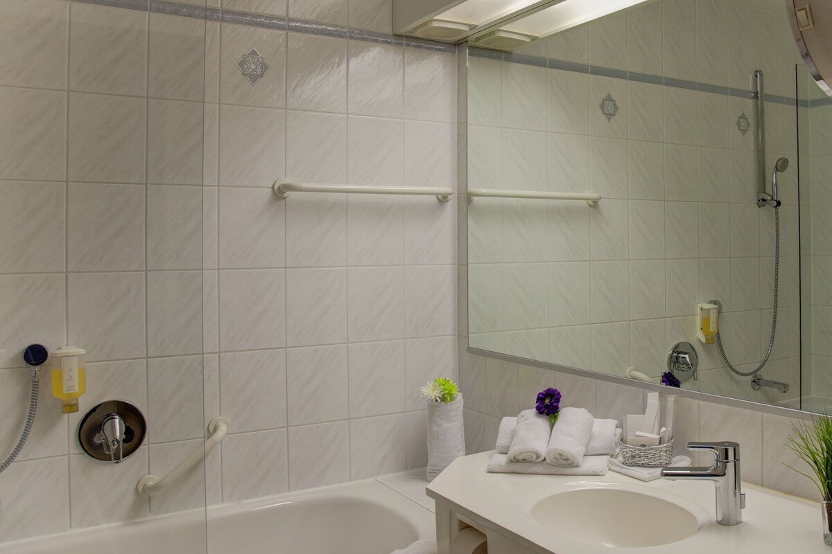 A modern bathroom with a bathtub, a sink, a mirror, and a shower.