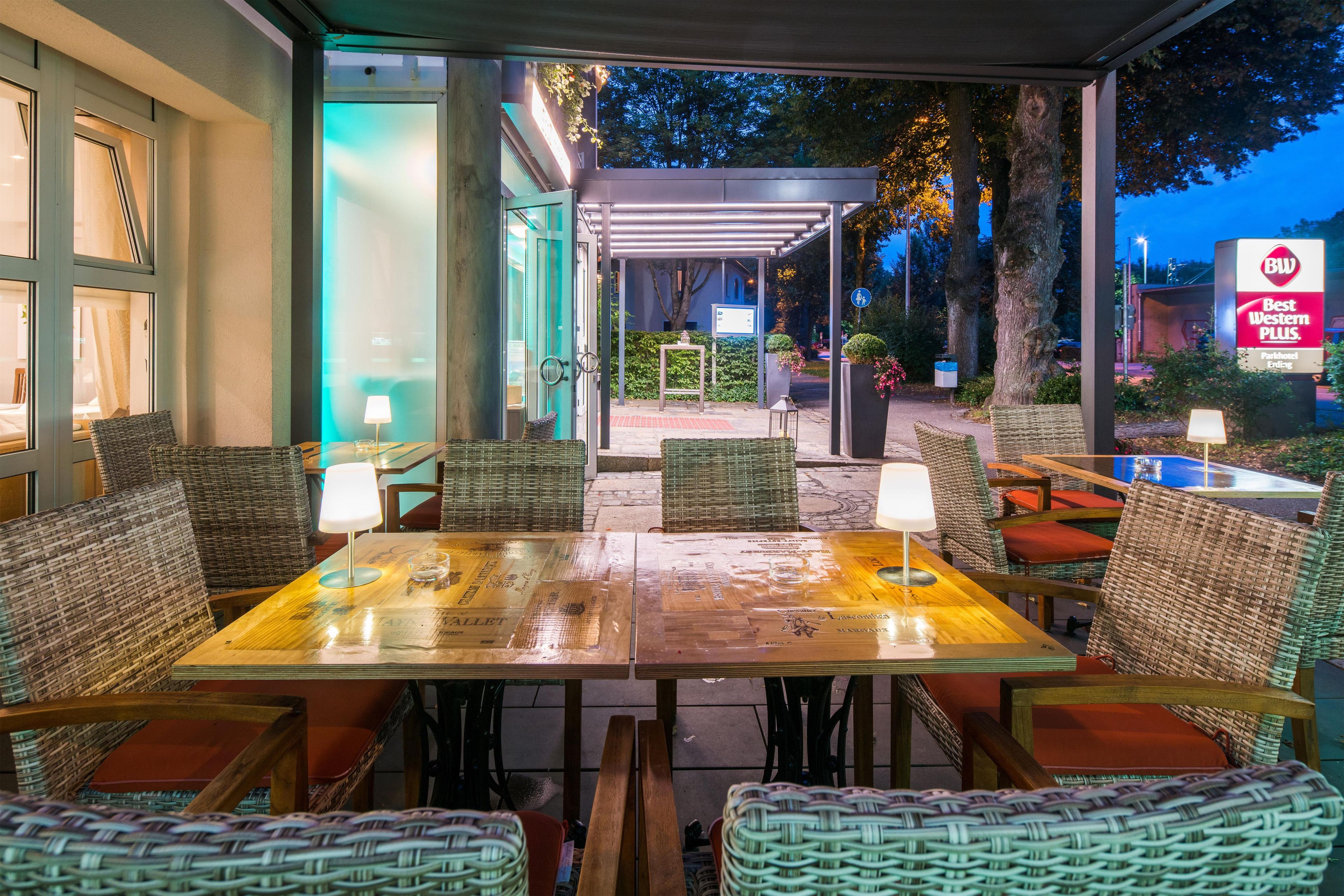 An outdoor seating area with wicker furniture and tables, a covered walkway, and a Best Western Plus sign.