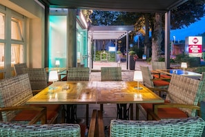 An outdoor seating area with wicker furniture and tables, a covered walkway, and a Best Western Plus sign. - Best Western Plus Parkhotel Erding (Erding)