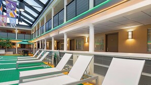 Eine Hotelhalle mit einem zentralen Atrium, mehreren Lounge-Sesseln und einer Glasdecke.