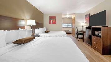 Habitación de hotel con dos camas, un escritorio, un televisor y un minibar.