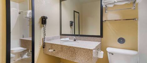 A bathroom with a granite countertop sink, a large mirror, a hairdryer, and a towel rack.