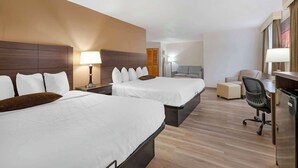 Ein Hotelzimmer mit zwei Betten, einem Schreibtisch, einem Stuhl und einem Kühlschrank.