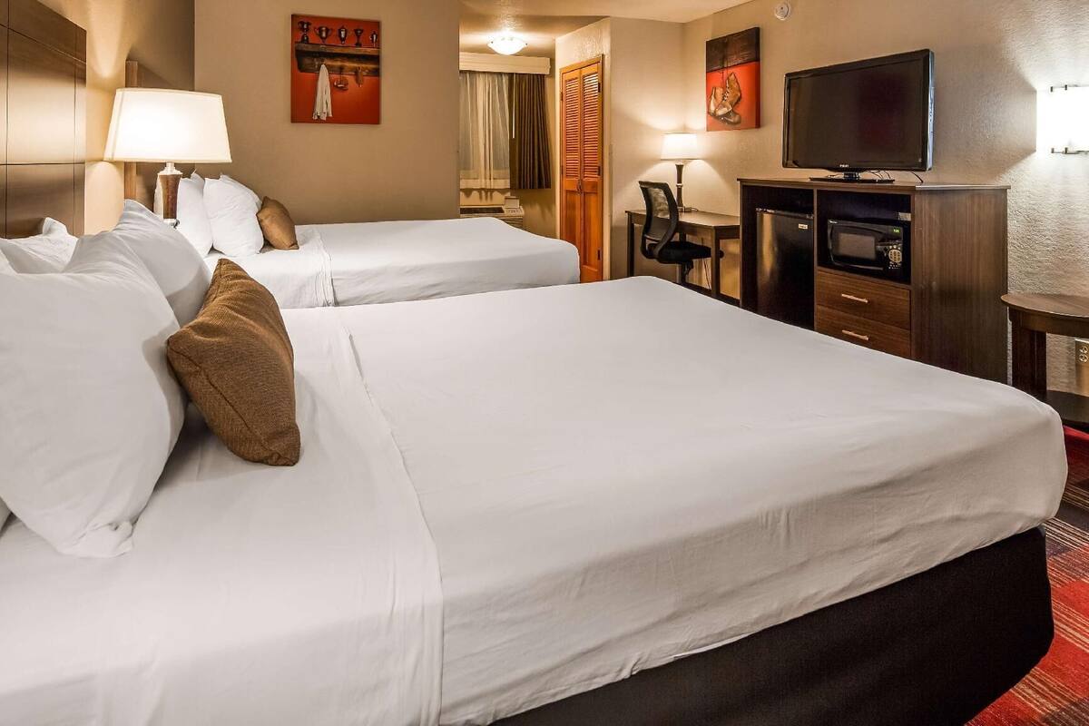 Une chambre d’hôtel avec deux lits, une télévision, un bureau et une chaise.