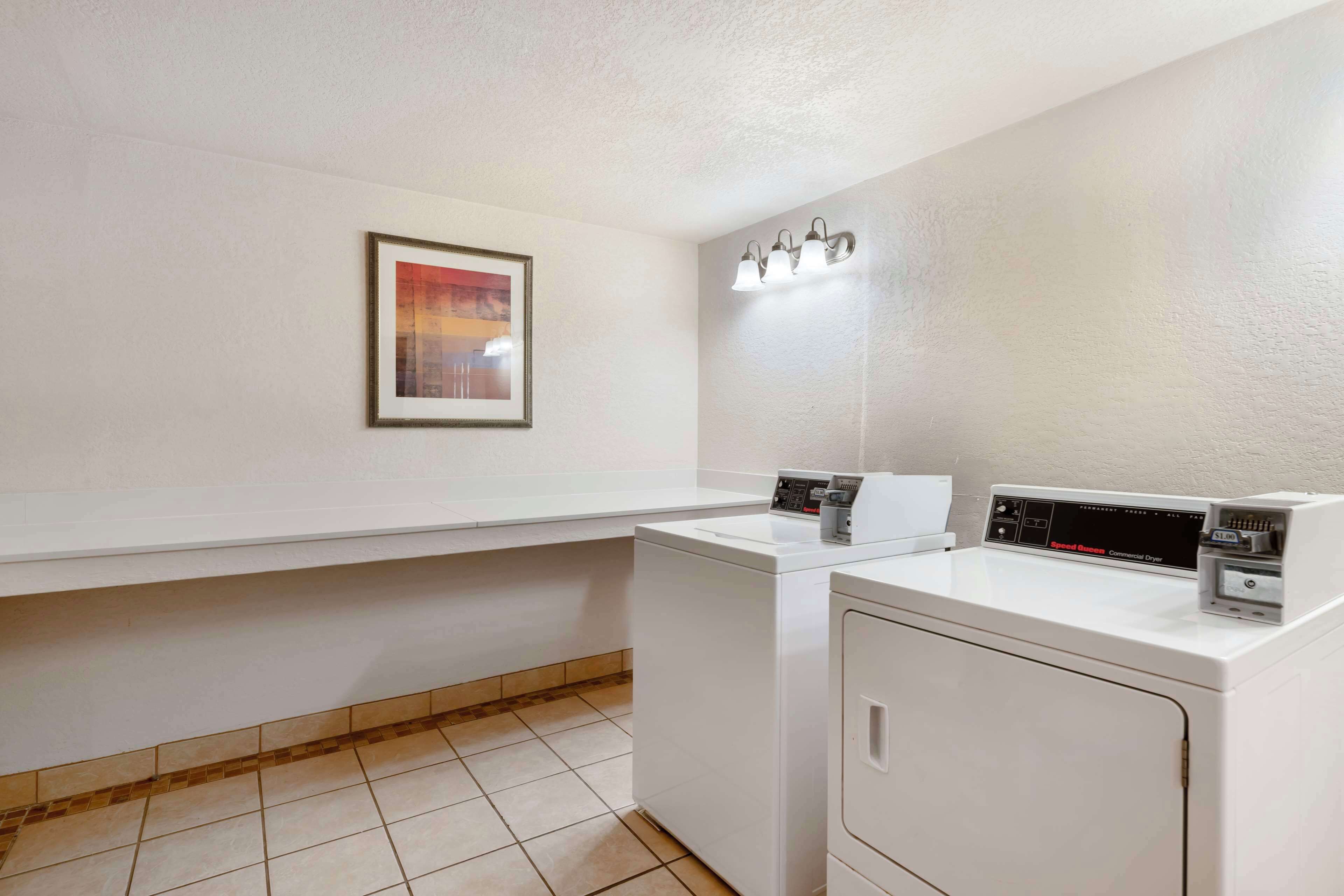 A laundry room with two washing machines, a countertop, and a wall-mounted light fixture.
